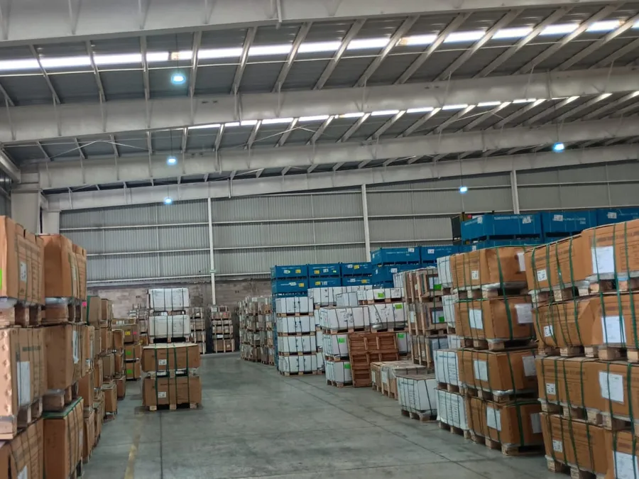 Almacén con tarimas de cajas y luminarias LED encendidas en el techo