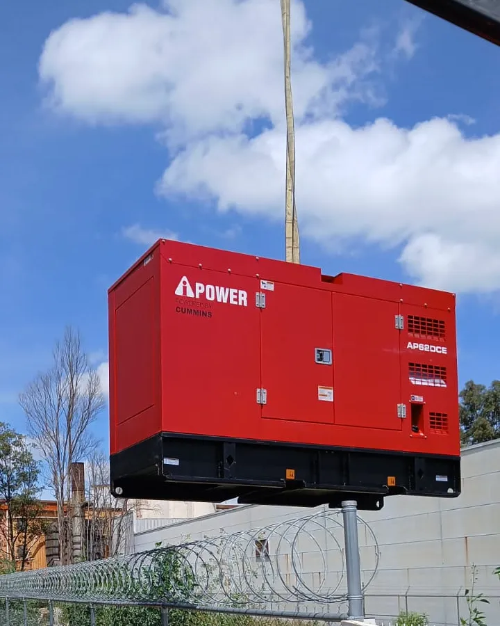 Planta de emergencia roja izada con una grúa, con cielo azul y una barda con alambre de navaja abajo